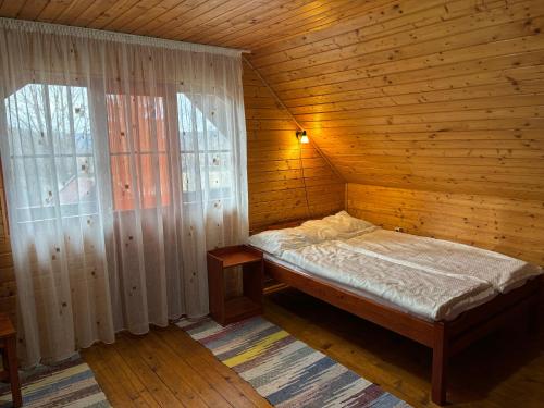 a bed in a wooden room with a window at Gergely Attila Vendégház in Izvoare