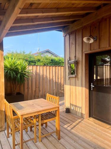 une table et des chaises en bois sur une terrasse en bois dans l'établissement La cabane du Broustic, à Andernos-les-Bains