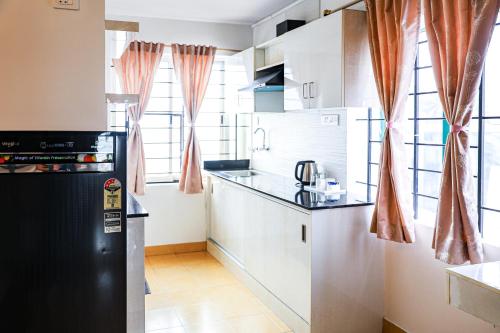 a kitchen with white cabinets and a black refrigerator at Hotel Vellara in Bengaluru