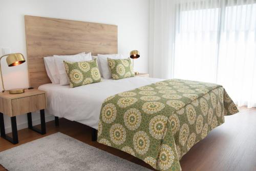 a bedroom with a large bed with a green comforter at Casa da Praceta - BY SCH in Alfeizerão