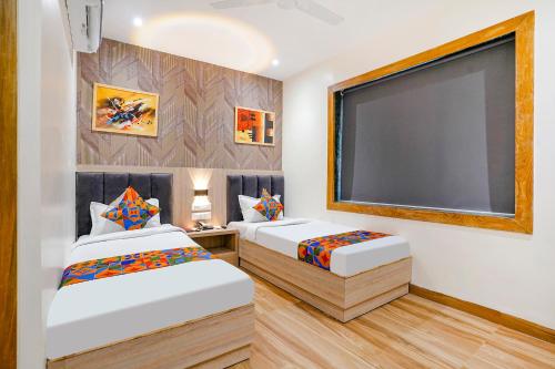 two beds in a room with a large screen at FabHotel Riza International - Nr Nesco Exhibition Centre in Mumbai