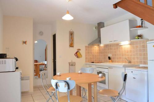 une cuisine avec une table en bois et des armoires blanches dans l'établissement SP340-008 Mais 2 pièces mezz 6 couchages SAINT PIERRE LA MER, à Saint Pierre La Mer