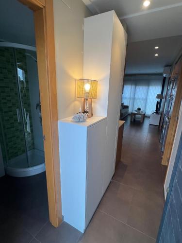 a lamp on a white cabinet in a hallway at MET Apto en Las Dunas, Oliva Nova in Oliva