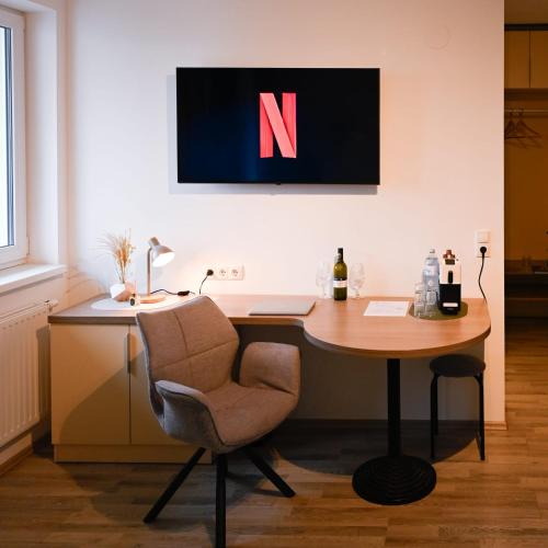 an office with a desk with a chair and a n on the wall at Aparthotel Neudörfl in Neudörfl