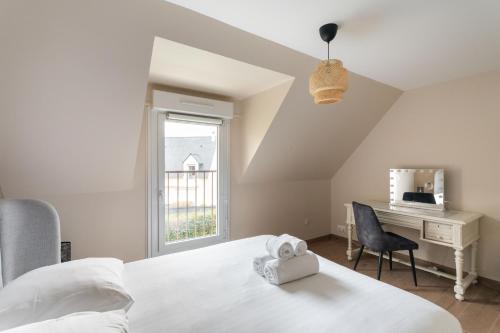 ein Schlafzimmer mit Bett, Schreibtisch und Fenster in der Unterkunft Chez Lisette - Maison climatisée dans Cancale in Cancale