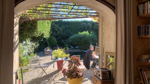 a man sitting in an archway looking out at a garden at La demeure in Eyguières