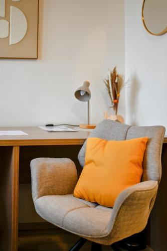 an orange pillow sitting on a chair next to a desk at Aparthotel Neudörfl in Neudörfl