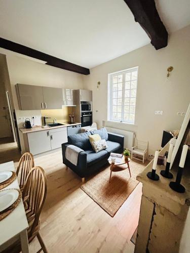 un salon avec un canapé bleu et une cuisine dans l'établissement Le clos du Tilleul - charme en hyper centre, à Caen