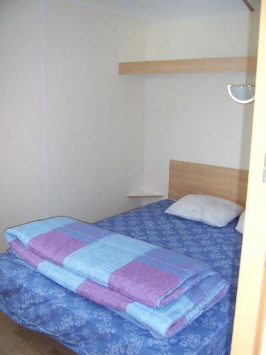 - une chambre dotée d'un lit avec des draps bleus et violets dans l'établissement Mobil-home 1 chambre 2 personnes à 15 min des Sables d'Olonne, à Vairé