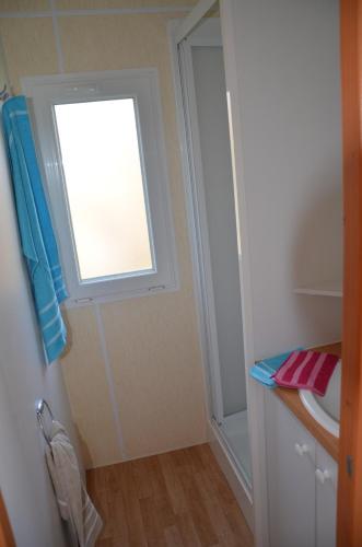 Elle comprend une petite salle de bains pourvue d'une fenêtre et d'un lavabo. dans l'établissement Mobil-home 1 chambre 2 personnes à 15 min des Sables d'Olonne, à Vairé