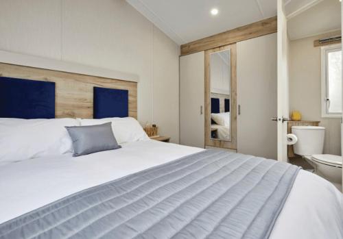 a bedroom with a large white bed and a bathroom at Trelawne Manor Holiday Park in Looe