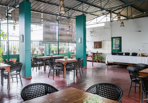 a restaurant with tables and chairs and windows at Hotel Vellara in Bengaluru