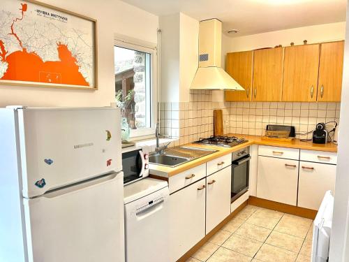 une cuisine avec des appareils électroménagers blancs et des armoires en bois dans l'établissement Maison lumineuse - Vue sur l'anse, à La Forêt-Fouesnant