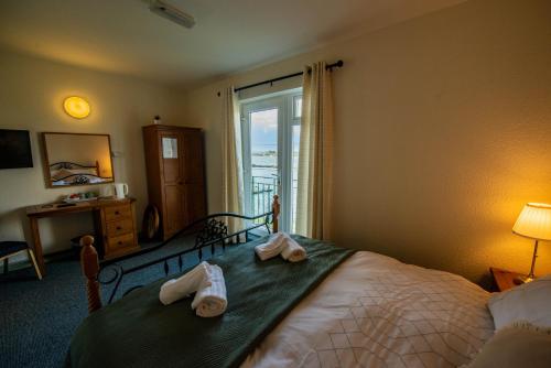 a bedroom with a bed with towels on it at Greenfield Lodge Hotel Bar & Bistro in Headford