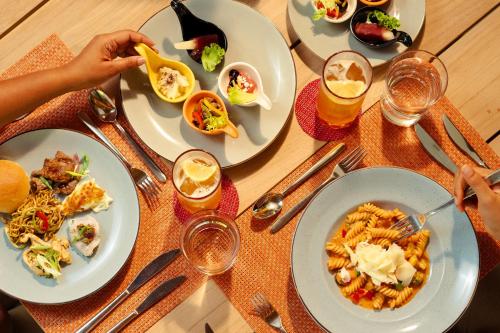a table topped with plates of food and drinks at RAAYA By Atmosphere - Premium All Inclusive with Free Transfers in Raa Atoll
