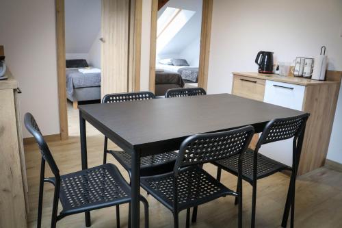 a black table and chairs in a kitchen with a bedroom at Sosnówka Pokoje Gościnne in Borne Sulinowo