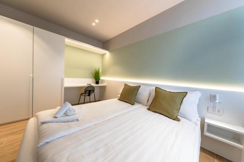 a bedroom with a large white bed with green pillows at Appartamenti BETTELONI in Bardolino