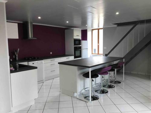 a kitchen with a black counter and stools in it at Maison au coeur de l Auvergne pour 15 personnes in Mareugheol