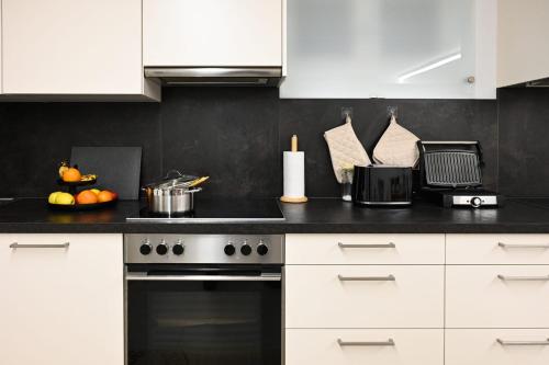 a kitchen with white cabinets and a stove top oven at Aparthotel Neudörfl in Neudörfl