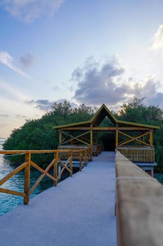 a wooden bridge over the water next to the ocean at Sun & Surf in Thulusdhoo