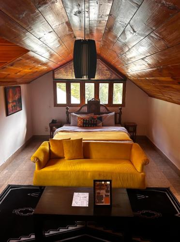 a bedroom with a bed and a yellow couch at Trout Lodges Naran in Naran
