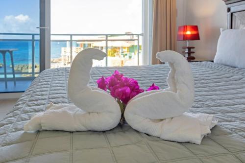due asciugamani a forma di cigno seduti su un letto con un fiore di Maho Beach House 1-Bedroom, Oceanfront Lifestyle a Maho Reef