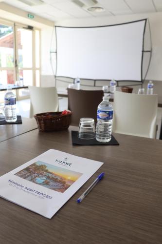 a book on a table with a pen and a bottle of water at Résidence Kaliopé in Le Lavandou
