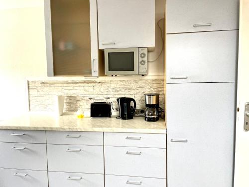 a kitchen with white cabinets and a microwave at Gemütliche Wohnung für 5 Personen, Playmobil, Palm Beach in Stein bei Nürnberg