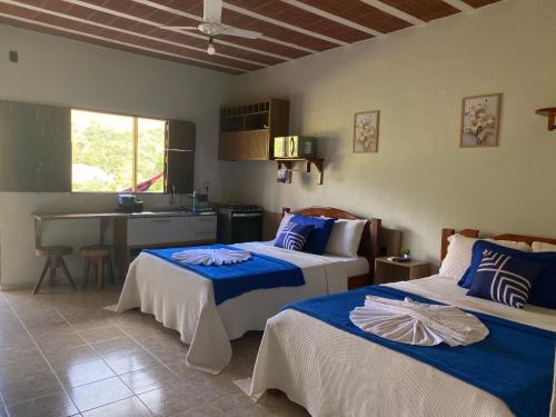 a bedroom with two beds and a kitchen at Flat Térreo condomínio Pedra do Rodeaoduro in Bonito