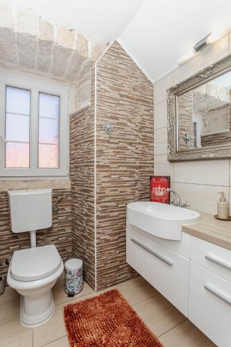 ein Badezimmer mit Toilette, Waschbecken und Spiegel in der Unterkunft Guesthouse Mimbelli in Orebić