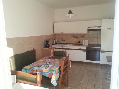 eine Küche mit einem Tisch und eine Küche mit weißen Schränken in der Unterkunft Apartment Jevic in Raslina