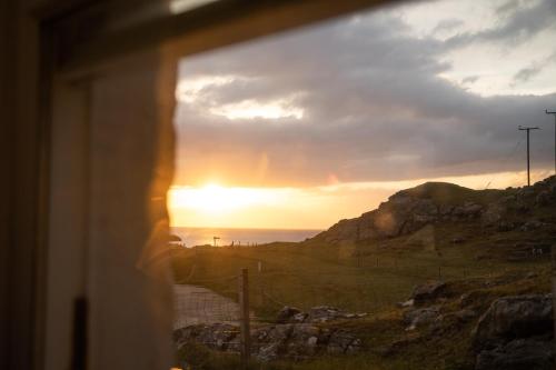 a sunset seen through a window of a building at Achmelvich Beach Youth Hostel in Achmelvich