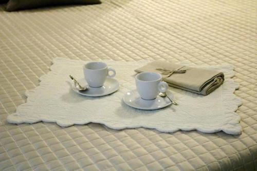 two coffee cups and a napkin on a bed at Venice Residence in Venice