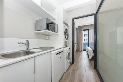 a white kitchen with a sink and a washing machine at The Regency Apartments in Pretoria