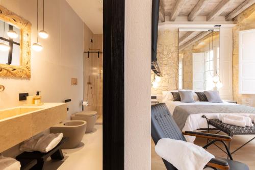 a bedroom with a bed and a bathroom with a sink at Pedra Bianca Luxury Rooms in Cagliari