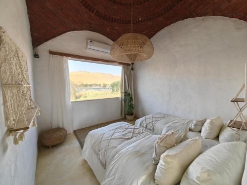 two beds in a room with a window at Nala Narty Boutique Hotel & Farm in Aswan