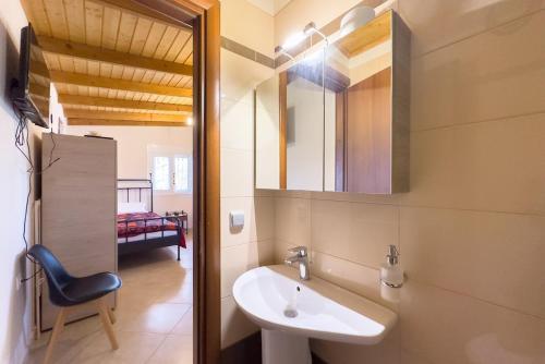 une salle de bain avec un lavabo, un miroir et une chaise dans l'établissement Elena's Home Apt 3, à Artemi