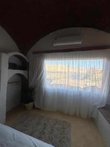 a bedroom with a white curtain and a window at Nala Narty Boutique Hotel & Farm in Aswan