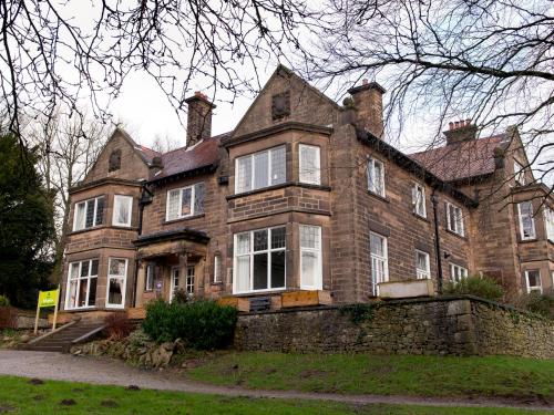 a large brick house with a stone wall at YHA Ravenstor in Millers Dale