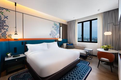 a hotel room with a white bed and a couch at Iconic Marjorie Hotel, Penang, a Tribute Portfolio Hotel in Bayan Lepas