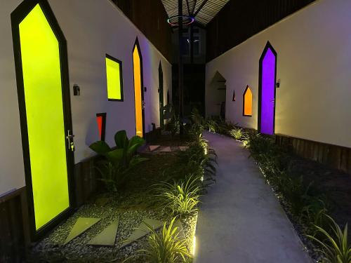 a hallway with green and purple doors and plants at Nhà Lười in Hue