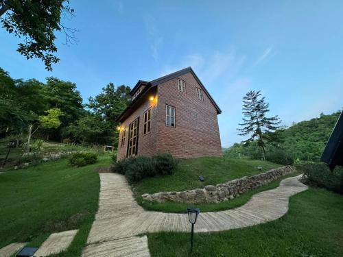 a brick building on a hill with a stone path at Ban Kaew Mo Ra Glamping & Restaurant in Pang Mapha