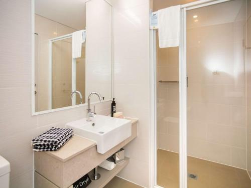bagno bianco con lavandino e doccia di Ibis Styles The Entrance a The Entrance
