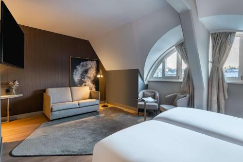 NH Collection Salzburg City في سالزبورغ: غرفة فندق مع سرير وكرسي