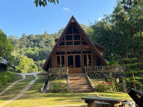 a cabin in the woods with a bench in front of it at Ban Kaew Mo Ra Glamping & Restaurant in Pang Mapha