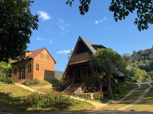 a house on a hill next to a road at Ban Kaew Mo Ra Glamping & Restaurant in Pang Mapha