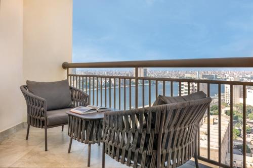 two chairs and a table on a balcony with a view at Sofitel Cairo Downtown Nile in Cairo
