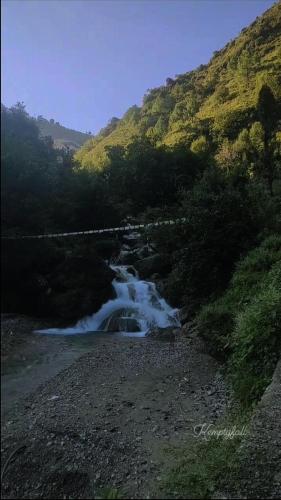a stream of water flowing down a hill next to a mountain at Sheetal Restaurant in Mussoorie