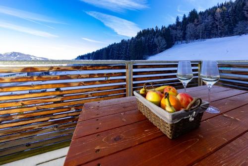 a basket of fruit and two wine glasses on a table at Appartement Klosterhügel in Haus im Ennstal
