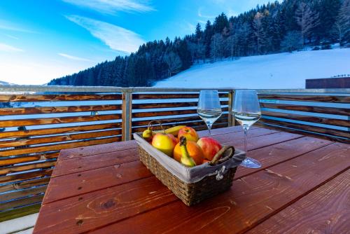 a basket of fruit on a table with two wine glasses at Appartement Klosterhügel in Haus im Ennstal